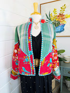 Colorful quilted jacket on a mannequin against a white wall with a plant in the background