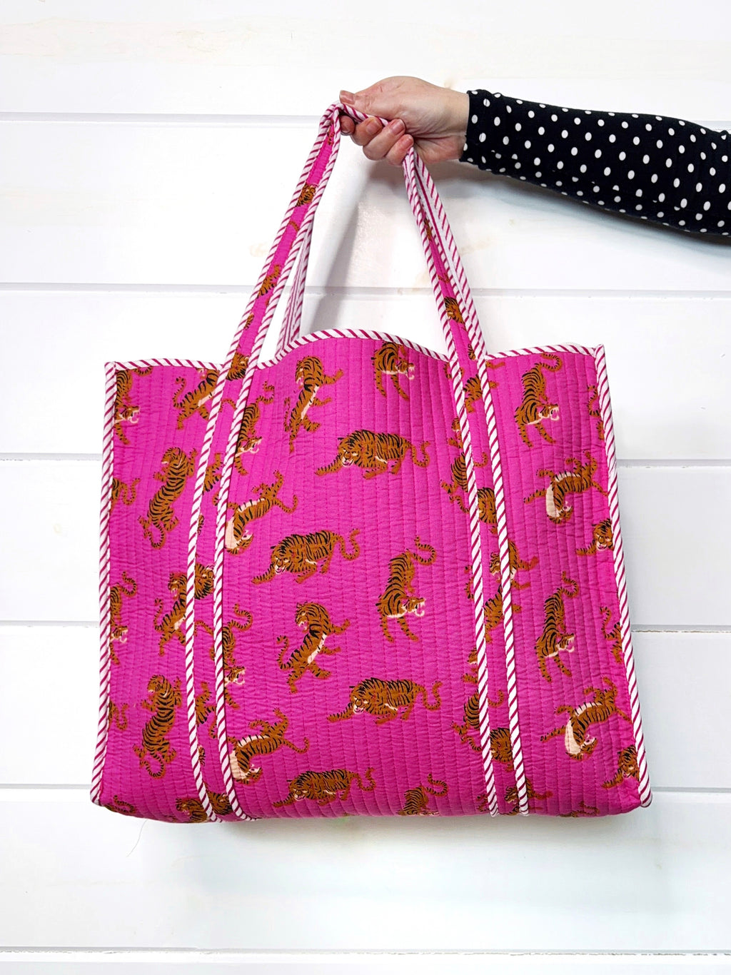 Folklore Couture Pink tote bag with tiger pattern held by a person on a white background