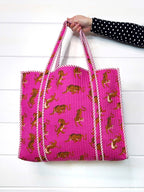 Folklore Couture Pink tote bag with tiger pattern held by a person on a white background