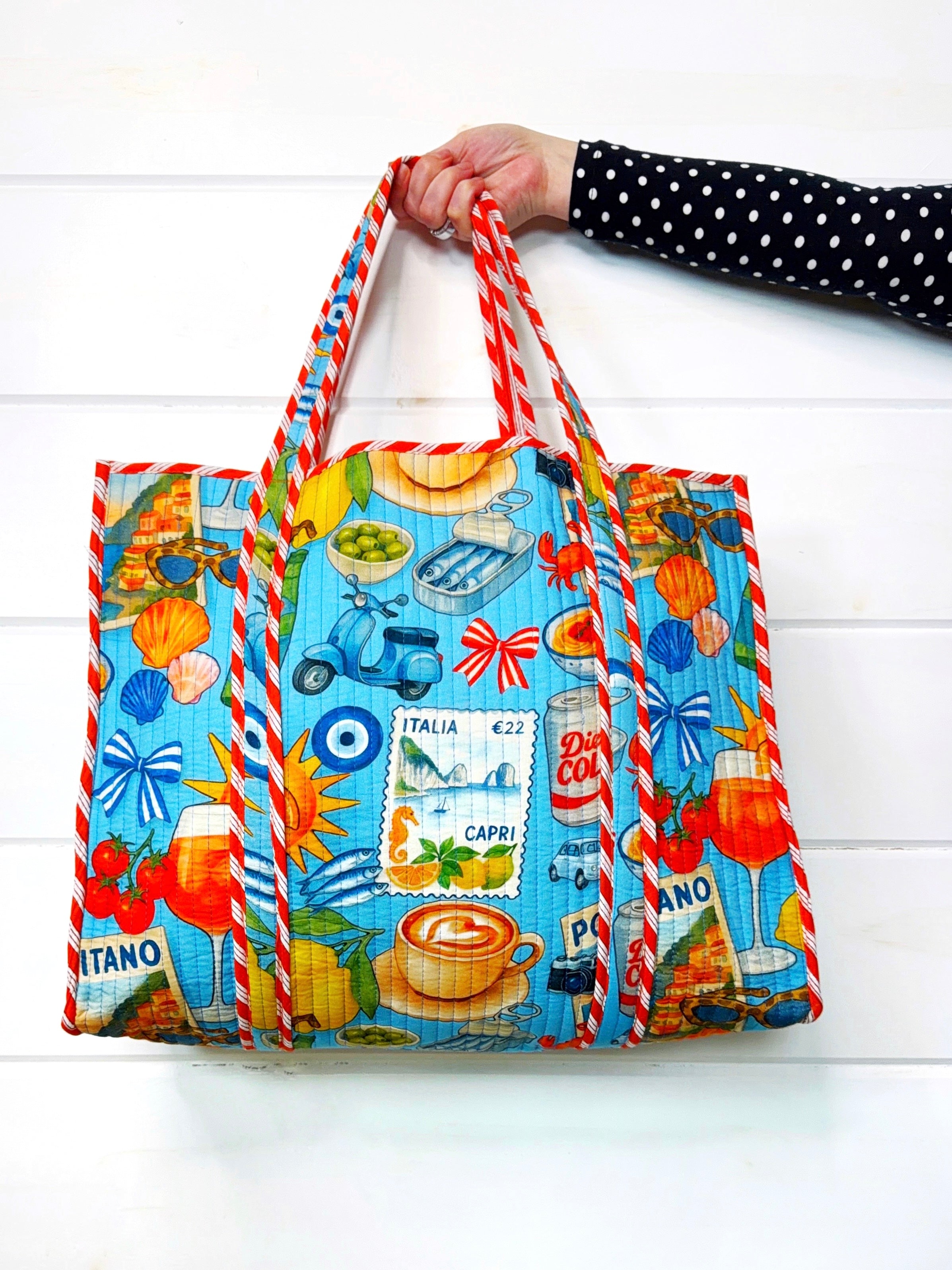 Colorful tote bag by Folklore Couture with Italian-themed design held by a person against a white background