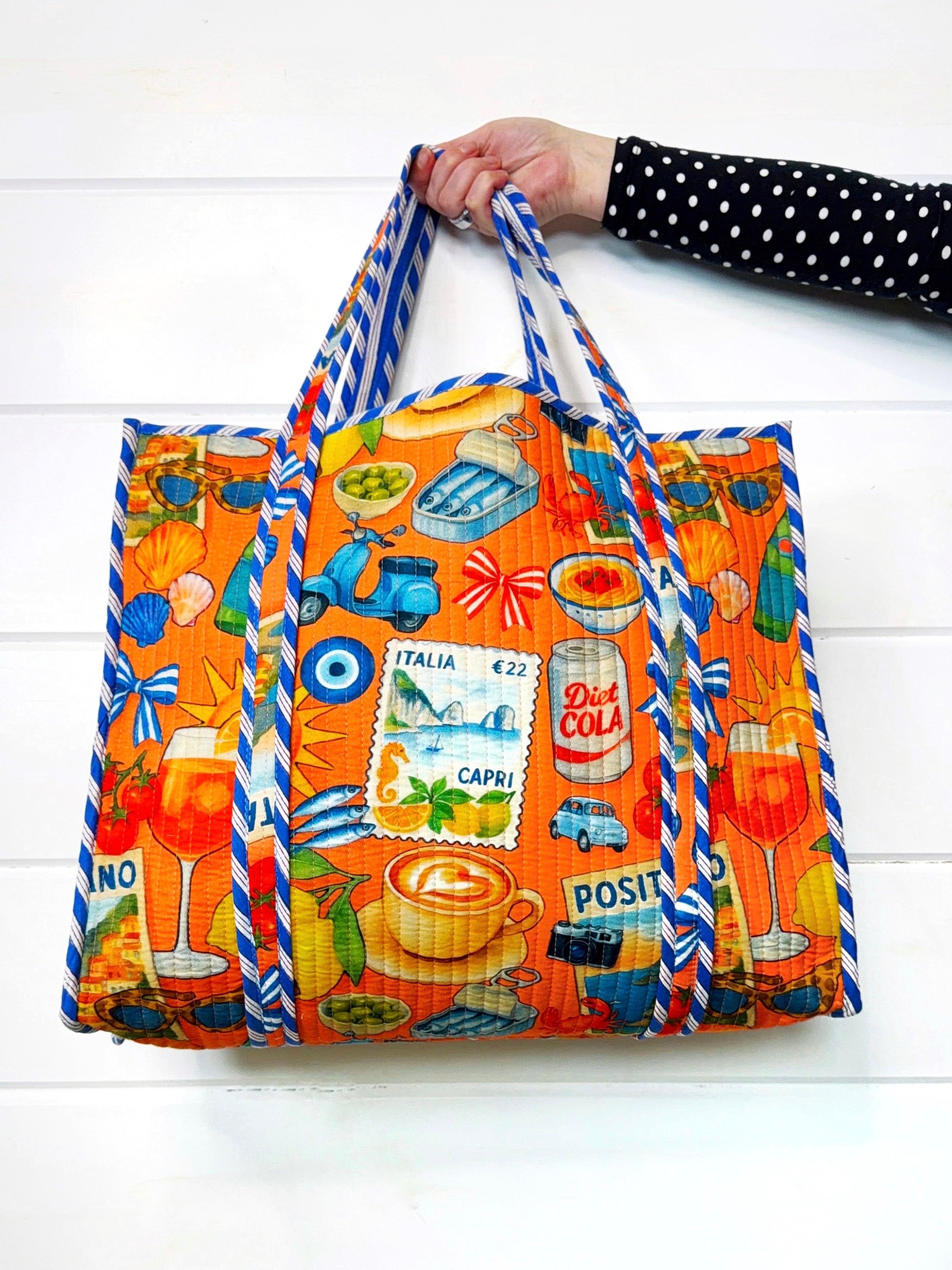 Colorful tote bag by Folklore Couture with various graphics held by a person on a white background