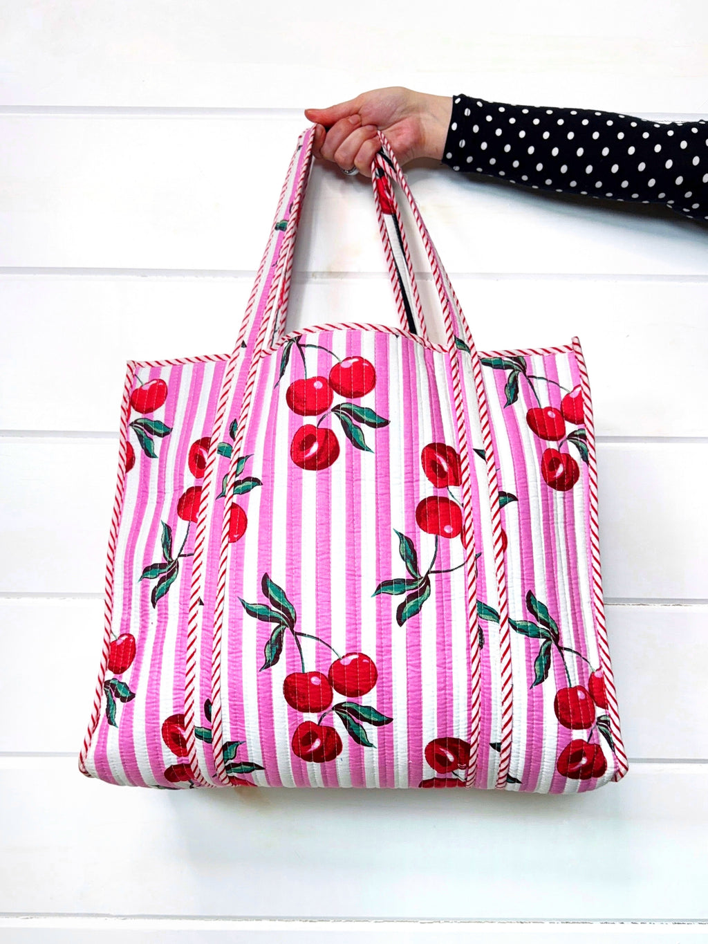 Folklore Couture Tote bag with cherry pattern held by a person on a white background