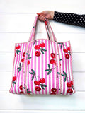 Folklore Couture Tote bag with cherry pattern held by a person on a white background
